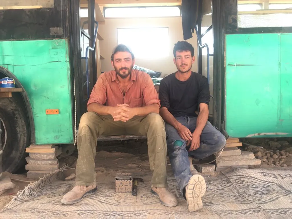 יותם ואריאל, מקימי אוטובוס בכרם, יושבים מול האוטובוס הירוק